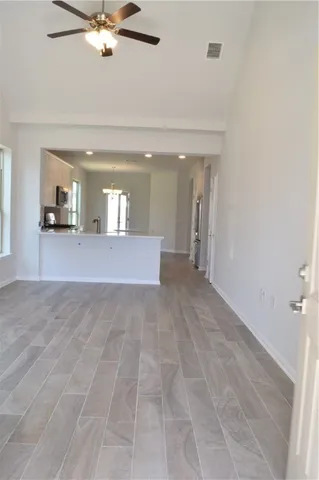 a view of a hallway with a chandelier fan and windows
