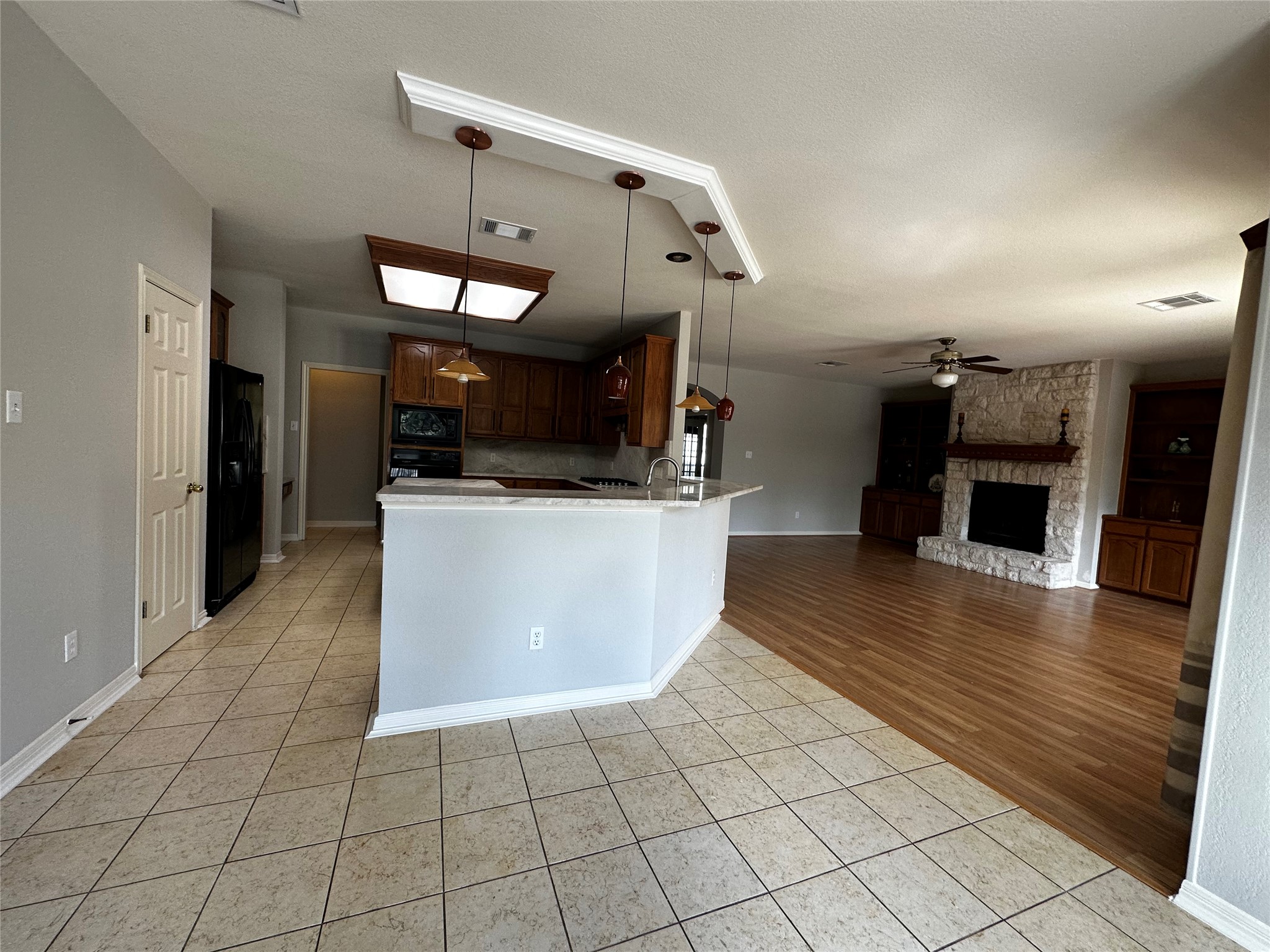 13615 Copperleaf Trail Manchaca, TX 78652 - Photo 39 of 39 Kitchen with light tile patterned flooring, open floor plan, decorative light fixtures, a stone fireplace, and a peninsula