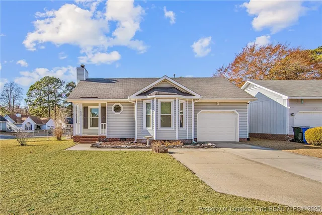 a view of a white house with a yard plants and large tree