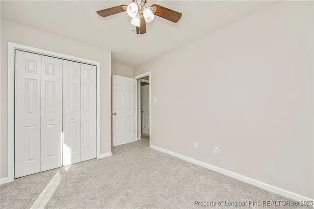 an empty room with windows and ceiling fan