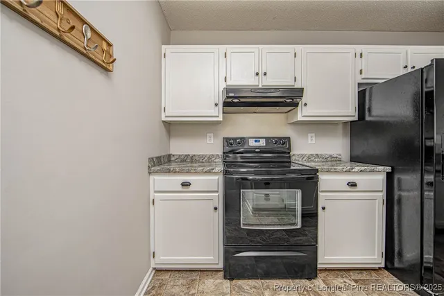 a kitchen with granite countertop a sink stove and refrigerator