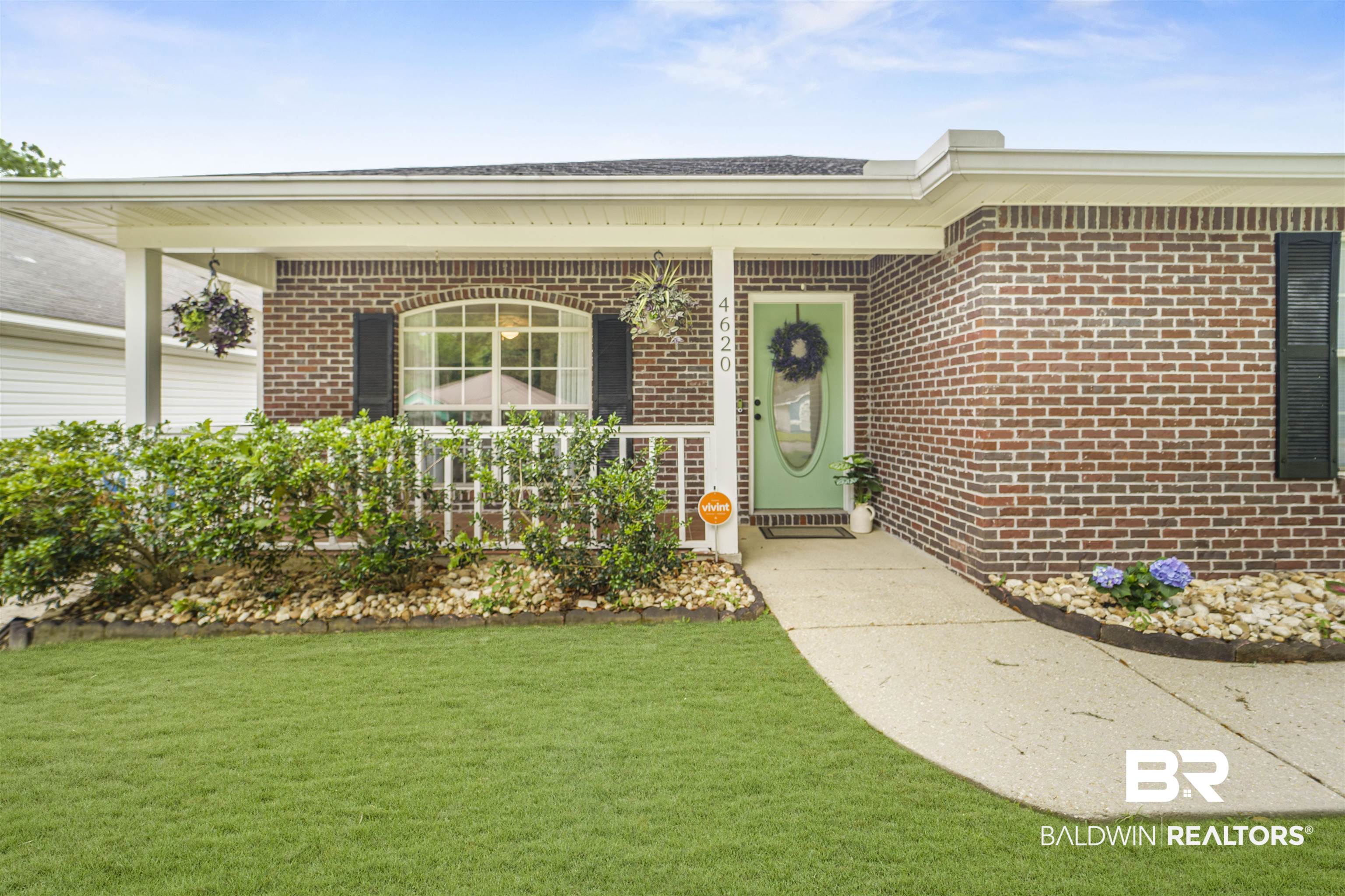 4620 Pine Boulevard Orange Beach, AL 36561 - Photo 5 of 49 Doorway to property featuring brick siding, a porch, and a lawn