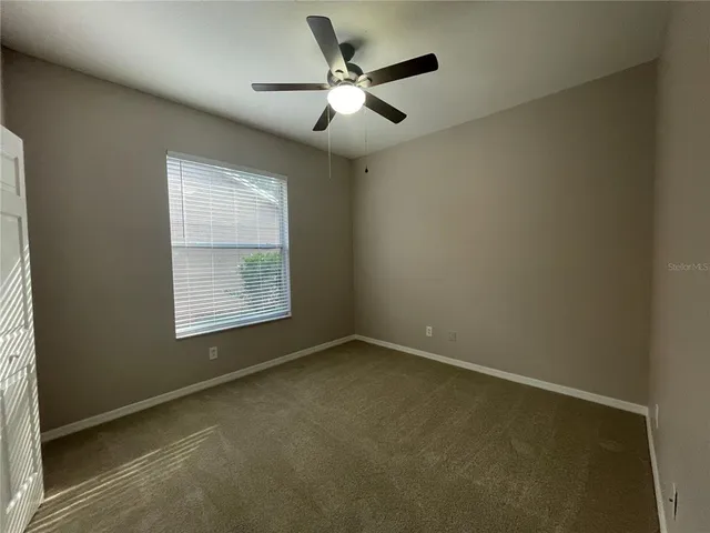 an empty room with a ceiling fan and window