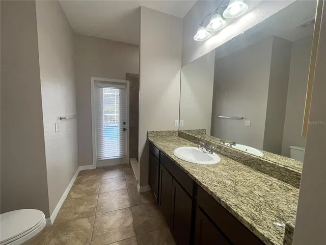 a bathroom with a granite countertop sink a toilet and a large mirror