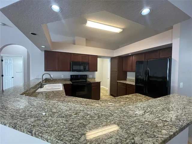 a kitchen with stainless steel appliances kitchen island granite countertop a refrigerator and a sink