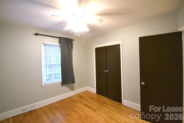 a view of an empty room with window and closet area
