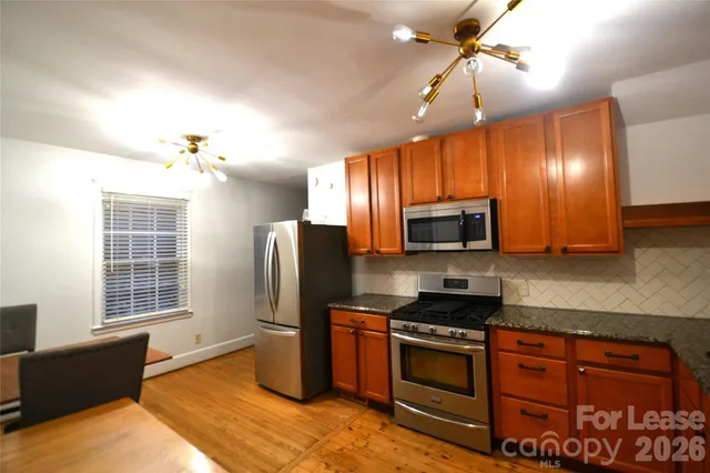 a kitchen with stainless steel appliances granite countertop a refrigerator and a stove top oven