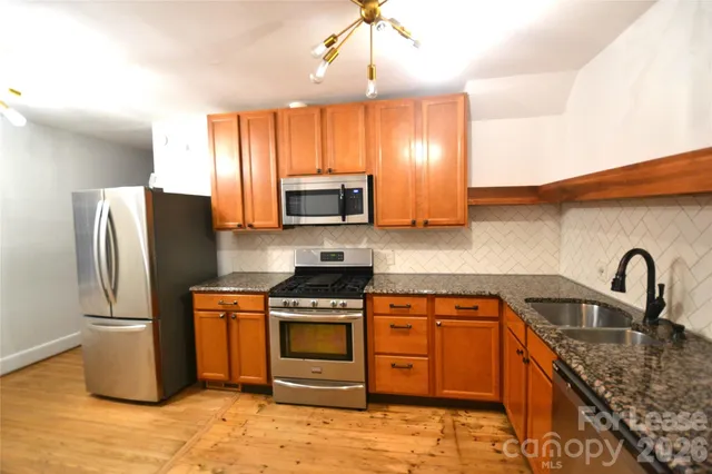 a kitchen with stainless steel appliances granite countertop a stove a sink dishwasher a refrigerator and a microwave