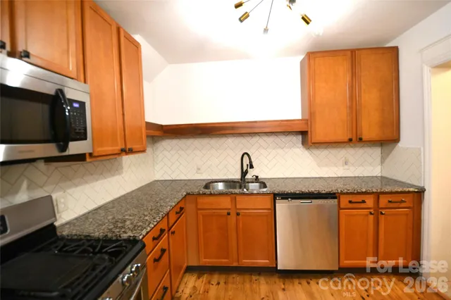 a kitchen with granite countertop a sink a stove and cabinets