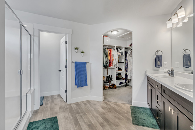 1577 Quailhill Road Saratoga Springs, UT 84045 - Photo 20 of 46 Primary bathroom with double vanity, light wood-style flooring, a stall shower, and a walk in closet