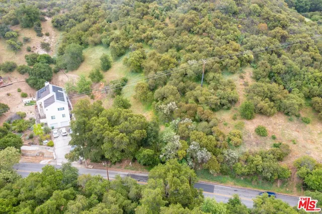 an aerial view of residential house with outdoor space and trees all around