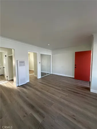 a view of an empty room with wooden floor and closet