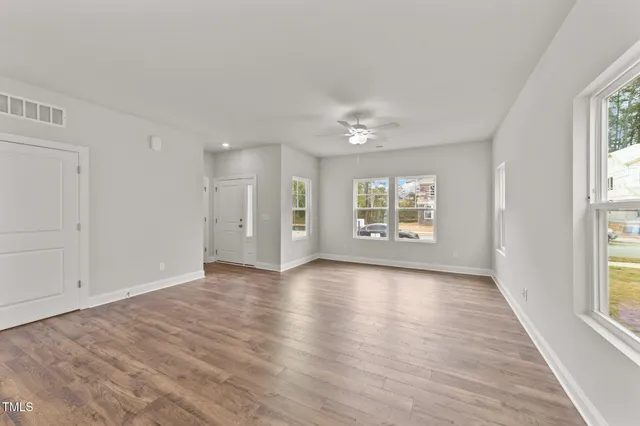 a view of an empty room with a window and wooden floor