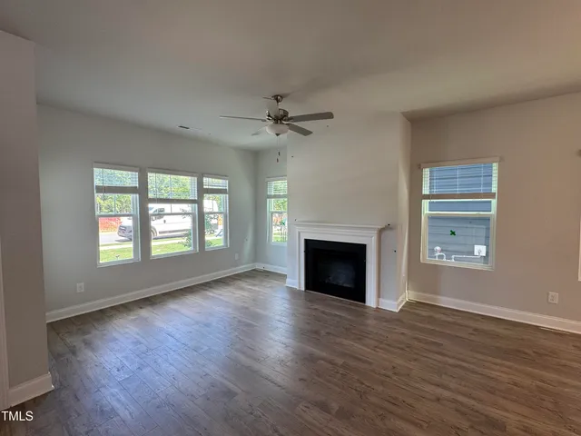 an empty room with windows fireplace and wooden floor