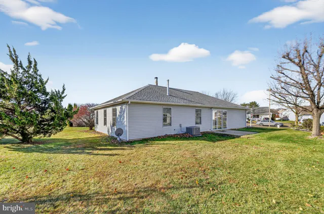 a white house that has a big yard and a large trees with wooden fence