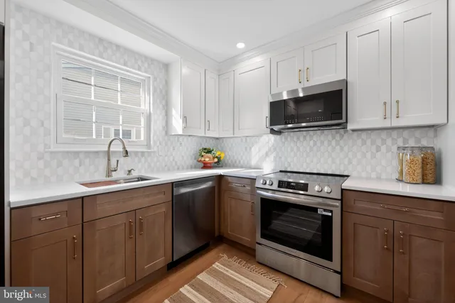a kitchen with cabinets stainless steel appliances a sink and a window