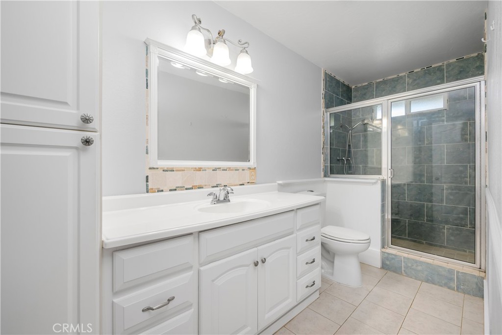16810 Tava Lane Riverside, CA 92504 - Photo 15 of 33 a bathroom with a toilet a sink a glass door a shower and a mirror