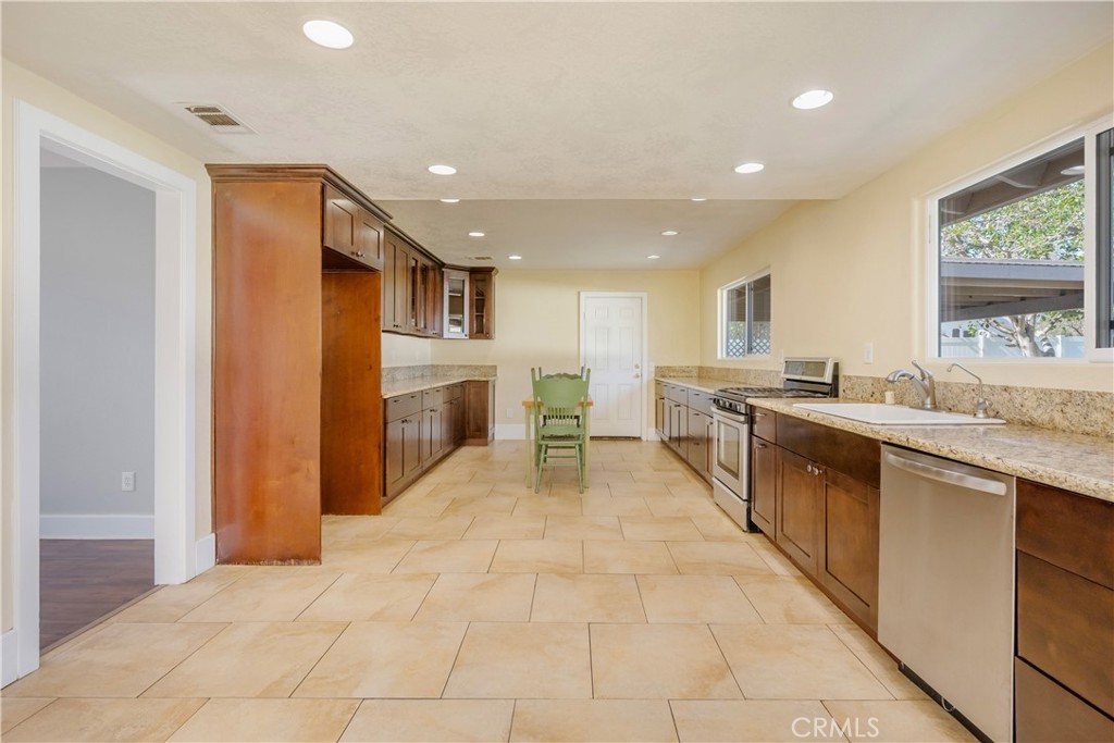 16810 Tava Lane Riverside, CA 92504 - Photo 6 of 33 a large kitchen with stainless steel appliances kitchen island granite countertop a refrigerator and a sink