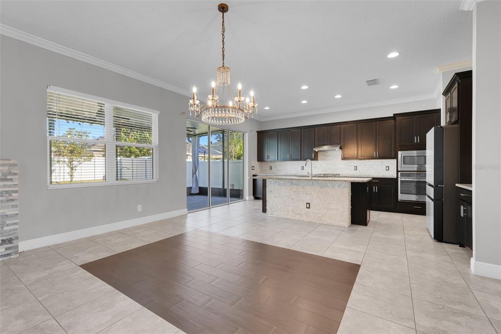959 Maypole Drive Apopka, FL 32703 - Photo 7 of 44 a kitchen with stainless steel appliances kitchen island granite countertop a refrigerator a sink dishwasher and white cabinets with wooden floor