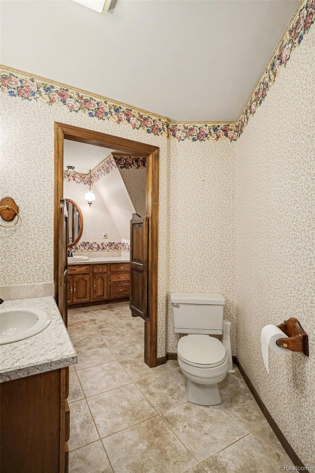 4425 North Henderson Road Davison, MI 48423 - Photo 20 of 43 Bathroom featuring a white toilet, light-colored tile flooring, and a vanity with a white countertop and wood cabinetry