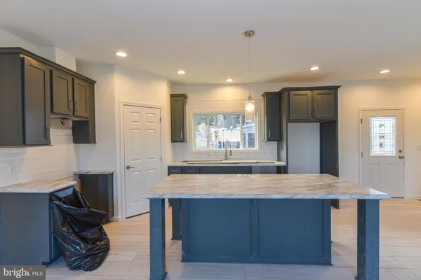 a kitchen with kitchen island granite countertop a sink cabinets and stainless steel appliances