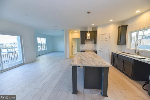 a large kitchen with kitchen island a sink dishwasher a stove and a refrigerator with wooden floor