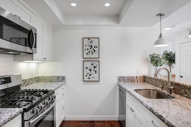a kitchen with stainless steel appliances granite countertop a sink stove and microwave