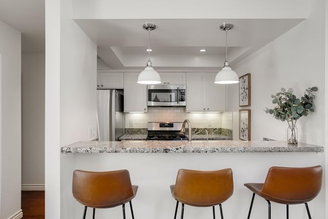 a kitchen with stainless steel appliances granite countertop a kitchen island a stove a sink a dining table and chairs