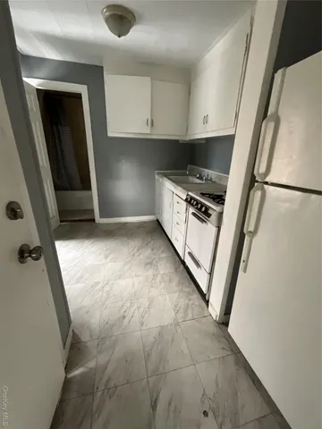a view of kitchen and empty room with wooden floor