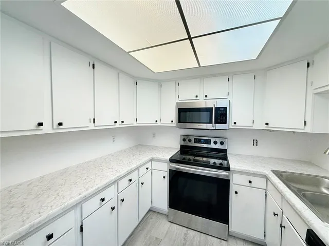 a kitchen with stainless steel appliances granite countertop grey cabinets a stove a sink and dishwasher