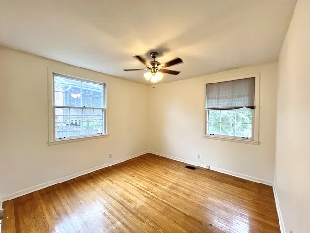 a view of an empty room with window and wooden floor