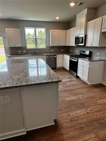 a kitchen with granite countertop a stove a sink and a microwave