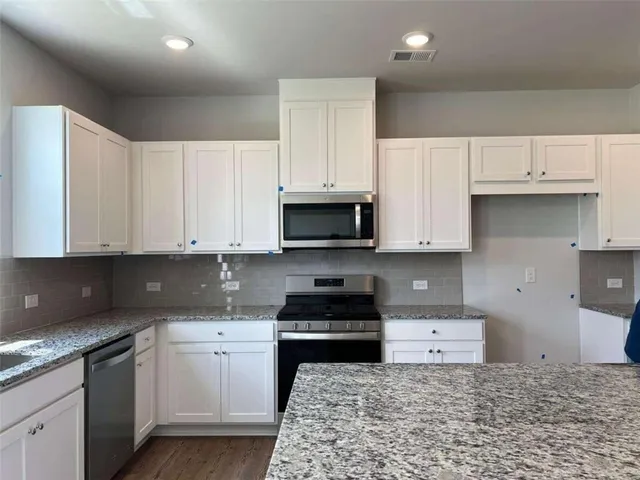 a kitchen with granite countertop a sink a stove and cabinets