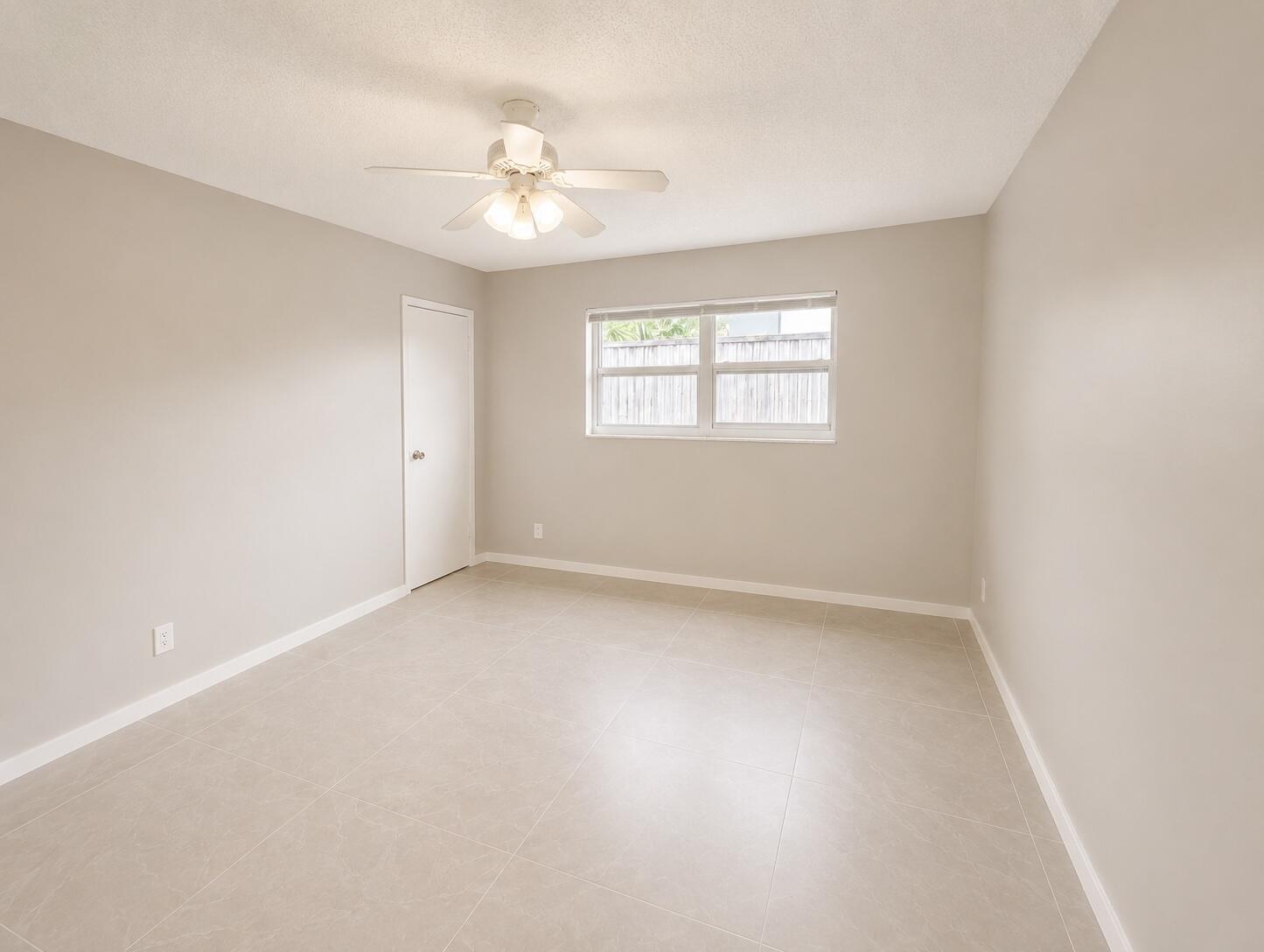 1794 Juno Road, Unit 2 North Palm Beach, FL 33408 - Photo 8 of 9 an empty room with a chandelier fan and windows