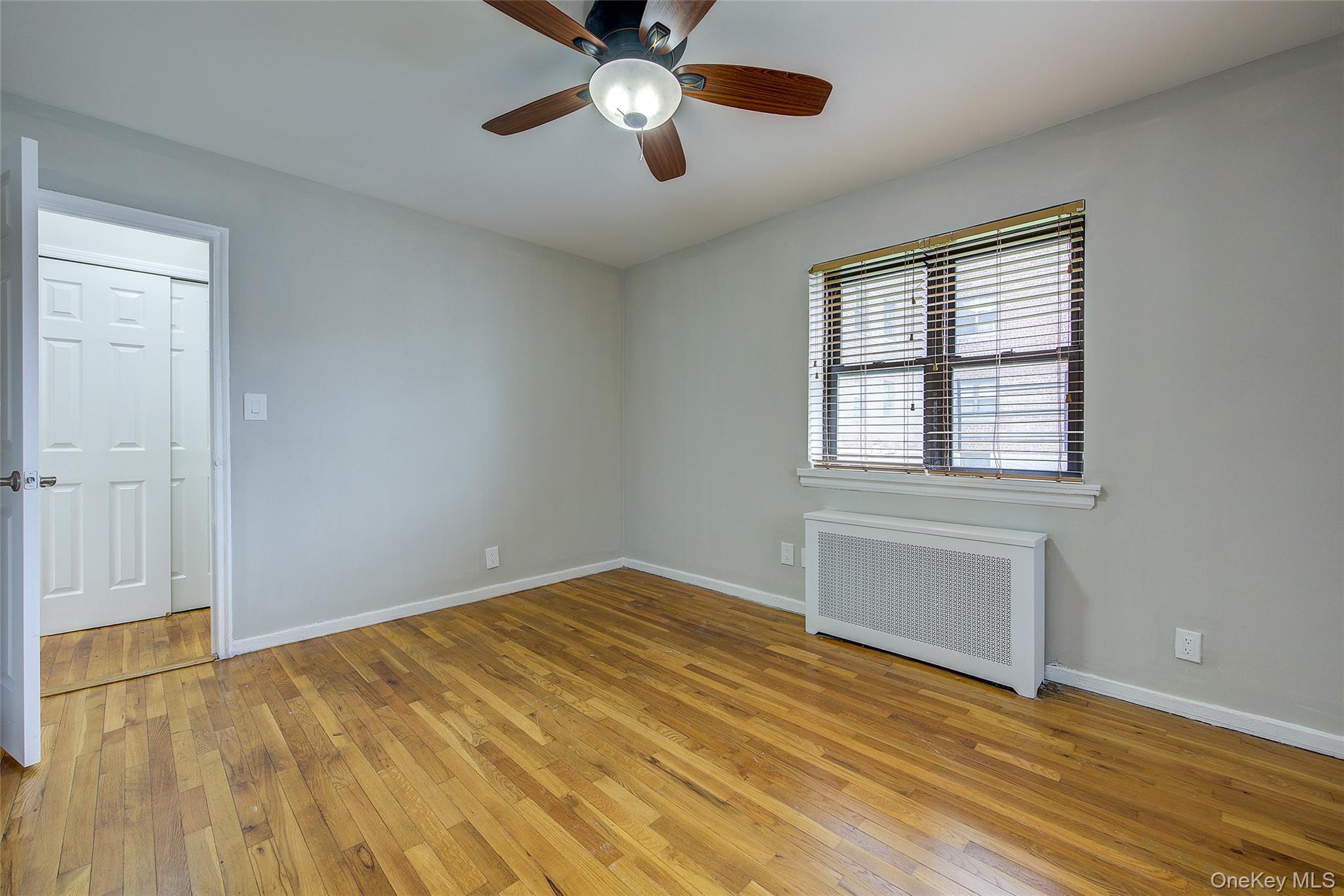 46-42 215th Place, Unit 1C Queens, NY 11361 - Photo 17 of 28 a view of empty room with wooden floor and fan