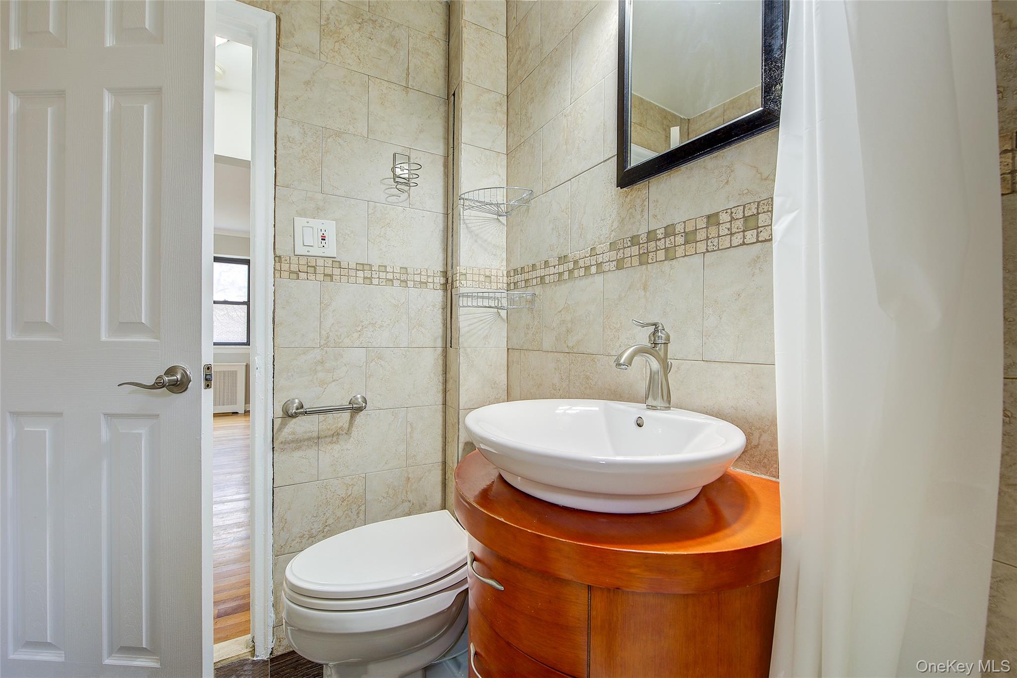 46-42 215th Place, Unit 1C Queens, NY 11361 - Photo 19 of 28 a bathroom with a sink a toilet and shower