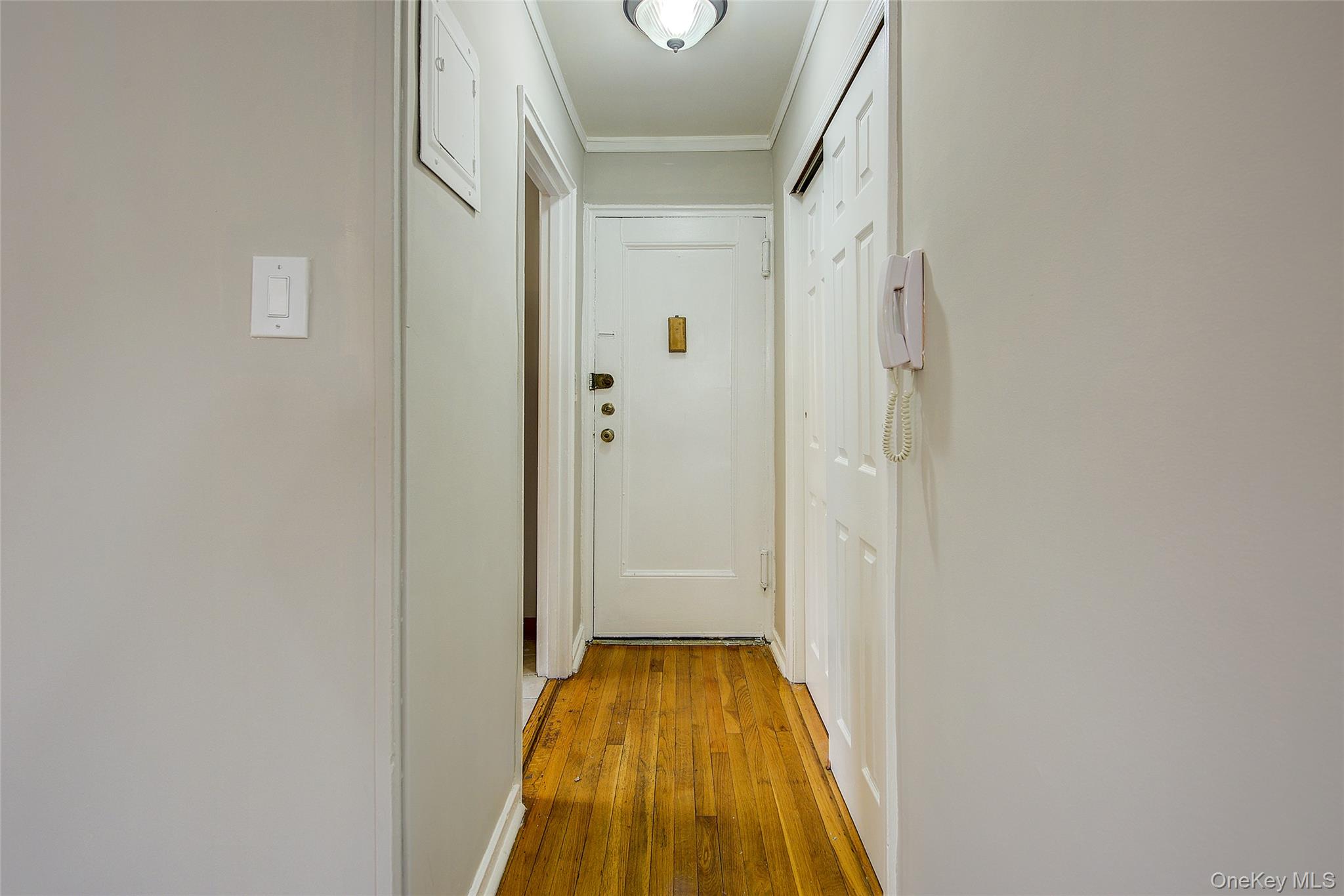 46-42 215th Place, Unit 1C Queens, NY 11361 - Photo 5 of 28 a view of a hallway with wooden floor and staircase