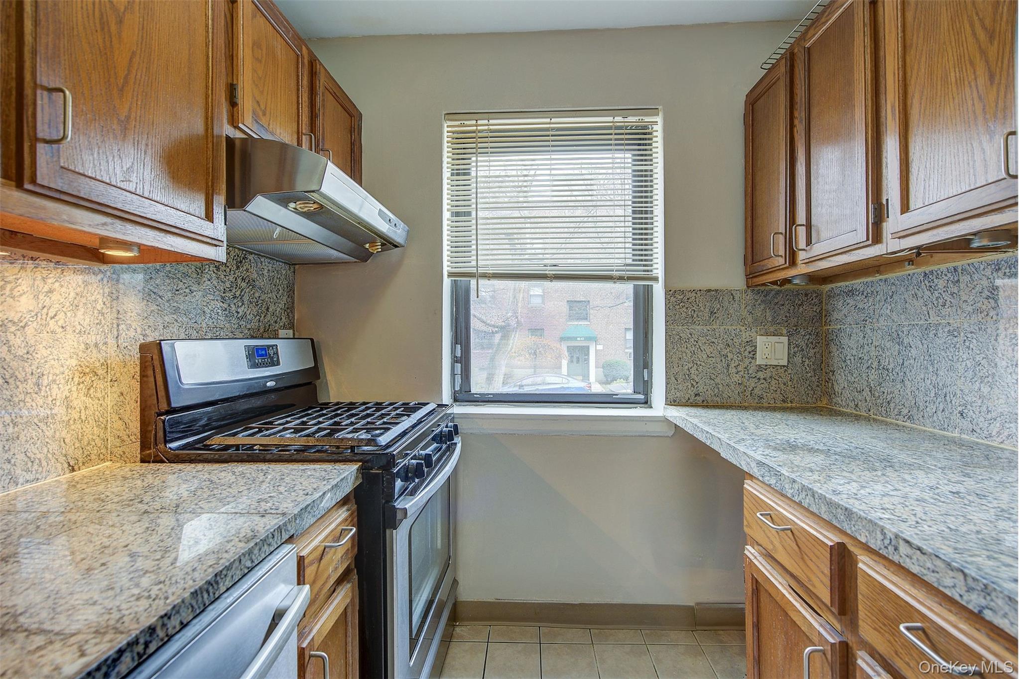 46-42 215th Place, Unit 1C Queens, NY 11361 - Photo 7 of 28 a kitchen with granite countertop a stove and a sink
