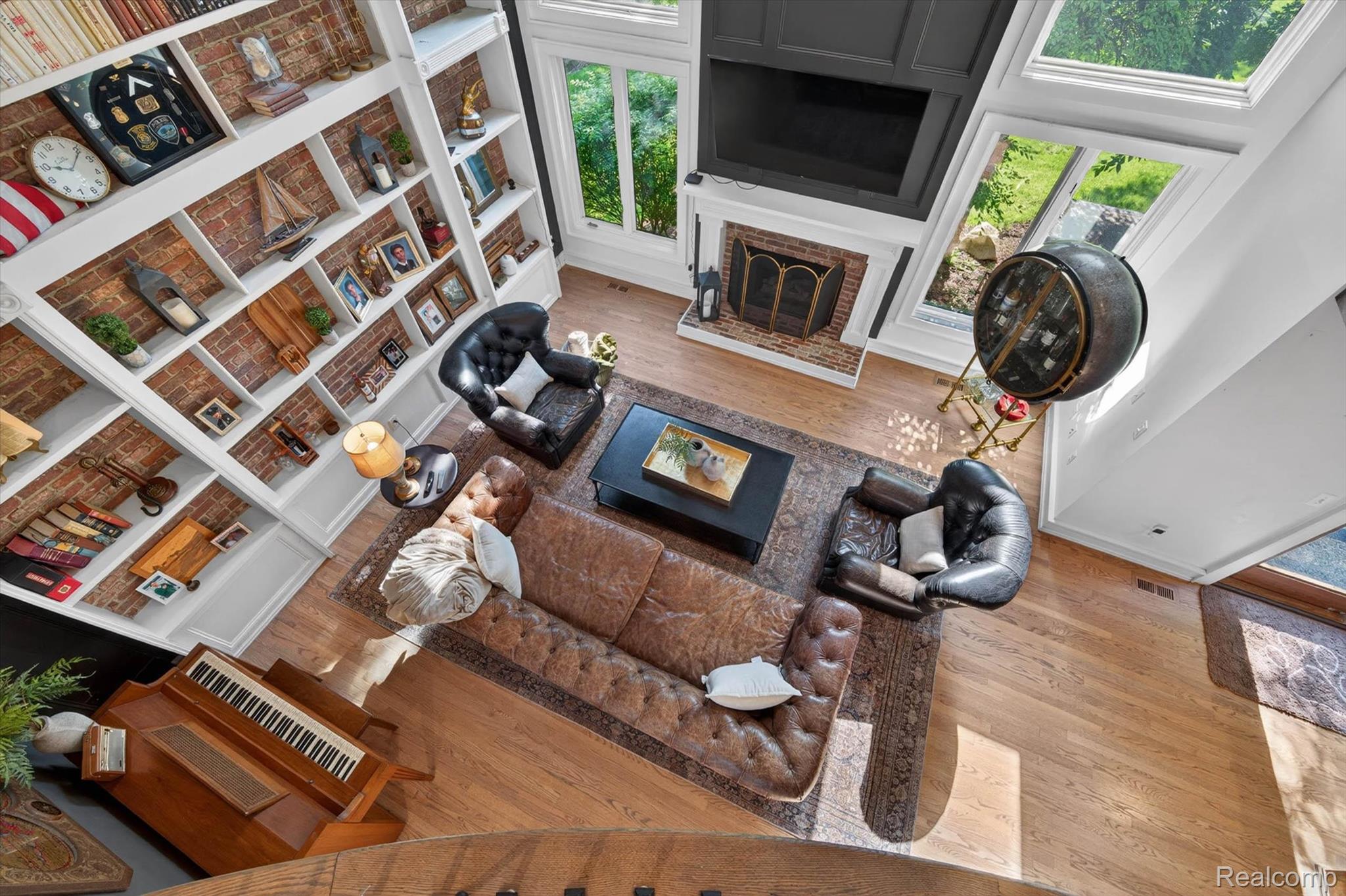 371 Lone Pine Circle Rochester, MI 48307 - Photo 25 of 59 Two-story living area featuring extensive built-in shelving with exposed brick backing, a fireplace with a decorative mantel, and high windows