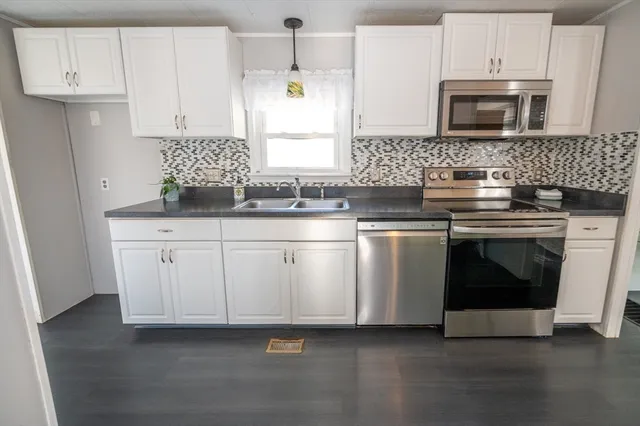 a kitchen with granite countertop white cabinets and white stainless steel appliances
