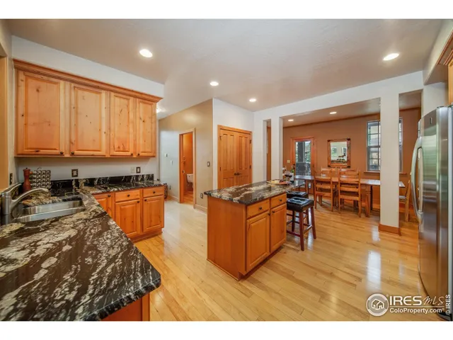 a living room with stainless steel appliances kitchen island granite countertop wooden cabinets a couch and a window