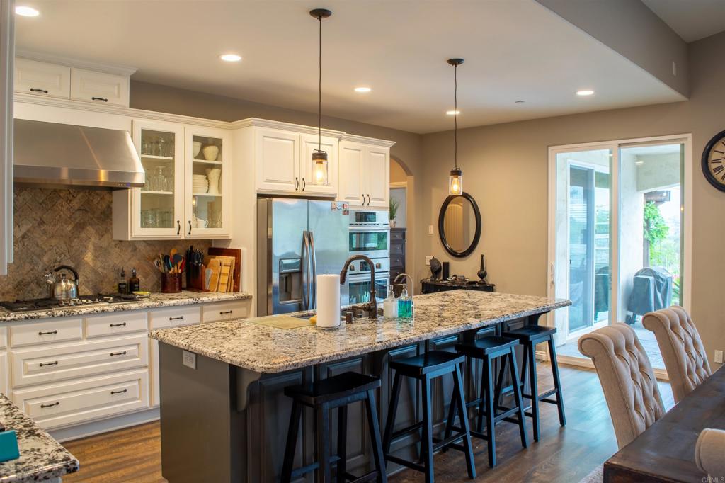 2521 Ralls Street Fallbrook, CA 92028 - Photo 12 of 43 a kitchen with granite countertop a table chairs and a wooden floor