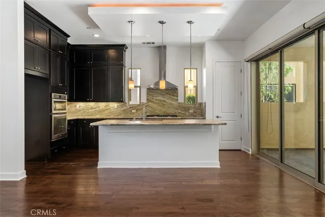 a view of kitchen with center island wooden floor appliances and cabinets
