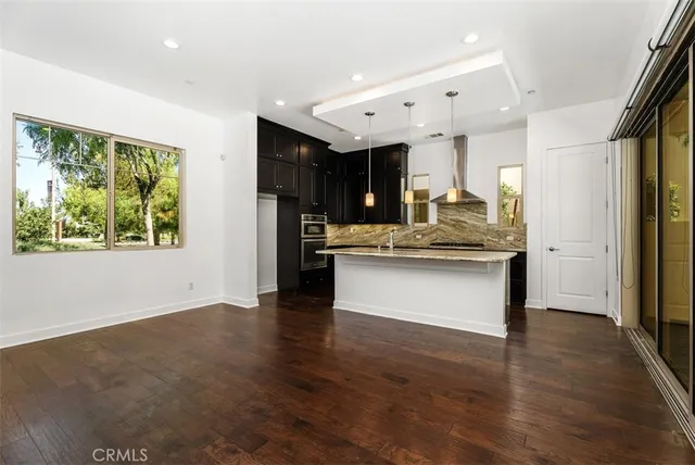 a kitchen with stainless steel appliances granite countertop a sink a stove and a wooden floor