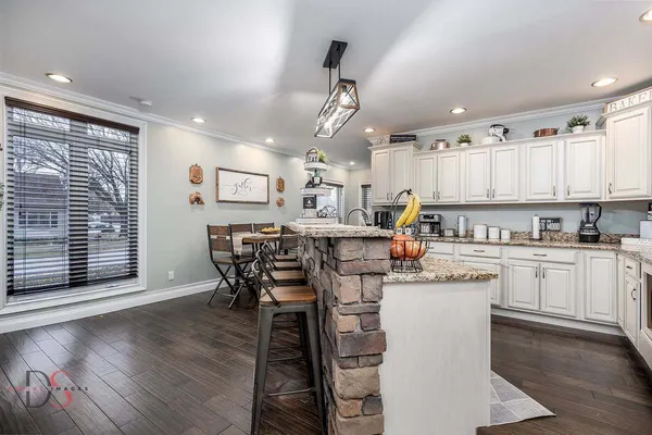 a kitchen with stainless steel appliances kitchen island granite countertop a table chairs sink and cabinets