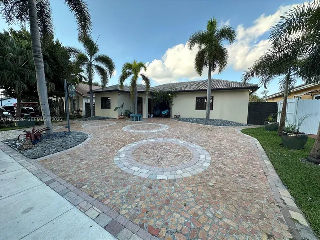 a front view of a house with a garden and tree