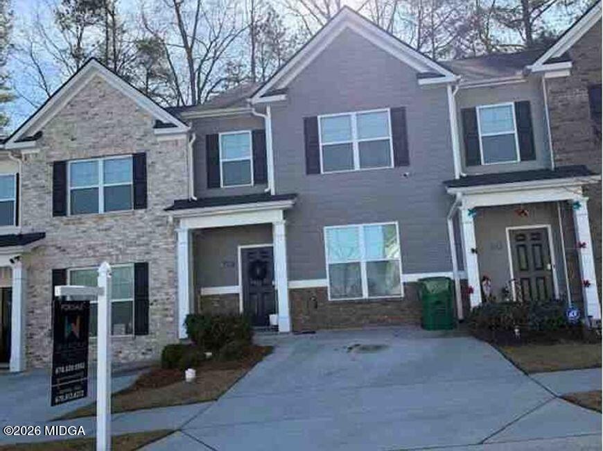 a front view of a house with yard and parking