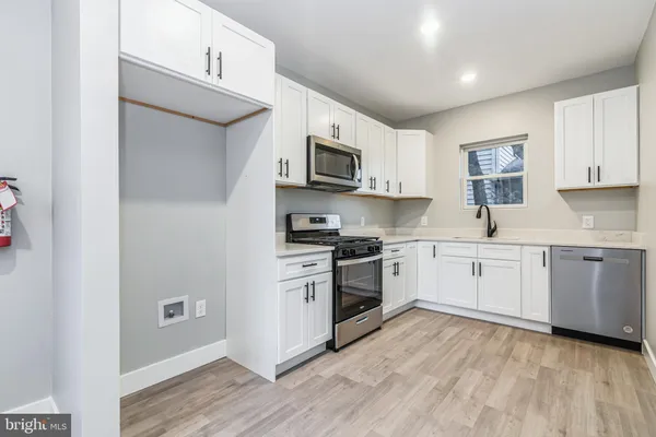 a kitchen with stainless steel appliances granite countertop a stove top oven a sink and dishwasher with wooden floor