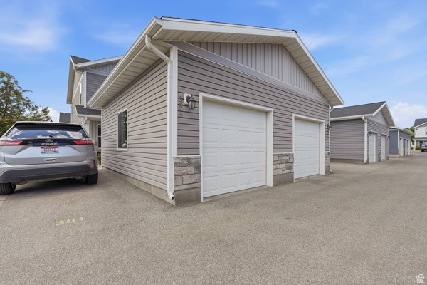 391 South 440th Street West Preston, ID 83263 - Photo 2 of 28 Two-car garage featuring white paneled doors, gray siding, and stone veneer accents