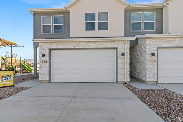 1264 West 500 South, Unit 320 Logan, UT 84321 - Photo 2 of 39 Modern townhouse exterior featuring a white garage door, stone veneer facade, and smooth stucco siding